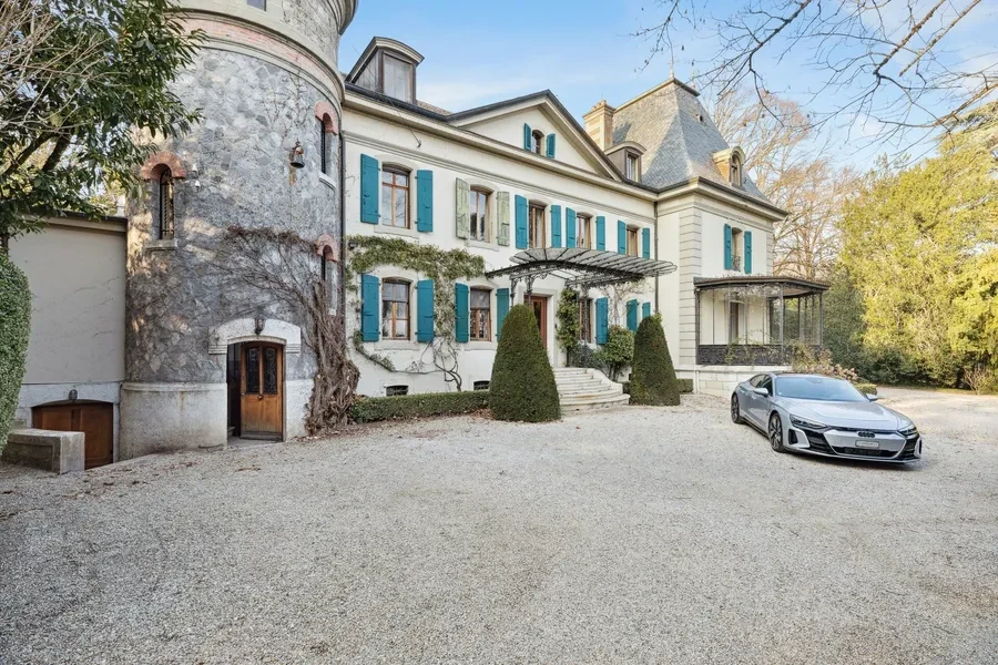 Historic Geneva estate Choulex — ground-level façade with turret, teal shutters and gravel forecourt