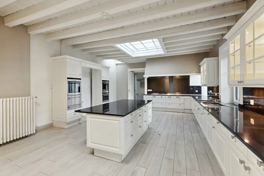 Historic Geneva estate Choulex — large kitchen with white cabinetry, central island, black granite countertops and skylight
