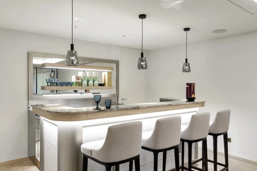 Cologny Geneva contemporary villa — private cocktail lounge with illuminated bar, marble countertop and bar seating
