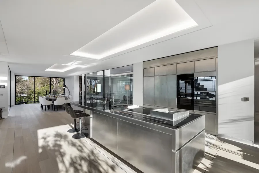 Cologny Geneva contemporary villa — professional kitchen with stainless steel island, integrated appliances and dining area