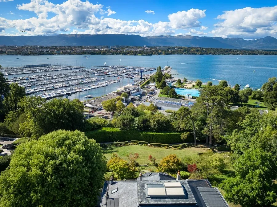 Cologny Geneva historic manor estate — aerial view over the private grounds with Lake Geneva marina and mountain backdrop