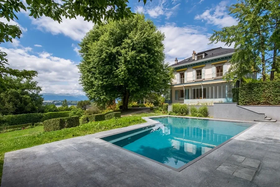 Cologny Geneva historic manor estate — outdoor swimming pool with main residence and Lake Geneva views beyond