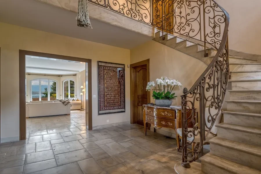 Domaine de Port-Noir Cologny Geneva — entrance hall with ornate wrought-iron staircase, marble steps and antique furnishings