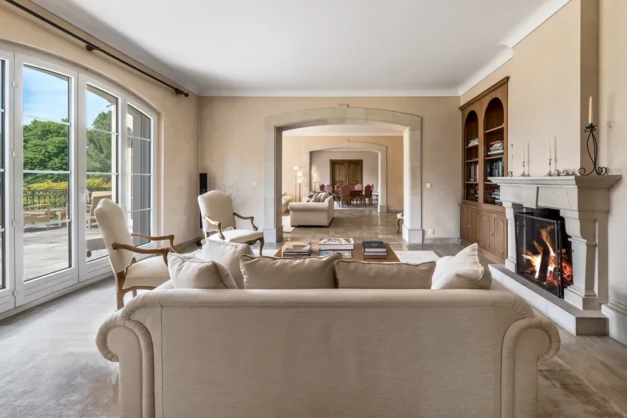 Domaine de Port-Noir Cologny Geneva — grand salon with open fireplace, arched doorways and French doors to the terrace