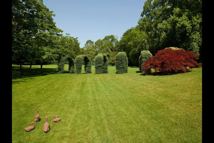 Formal topiary garden with sculpted hedges and red maple