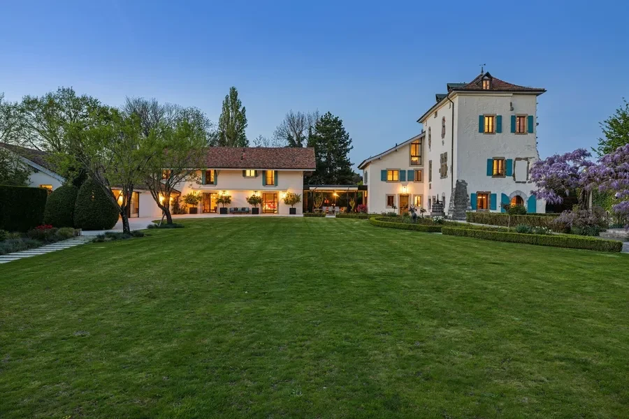 Historic château exterior with historic tower and manicured lawn at dusk