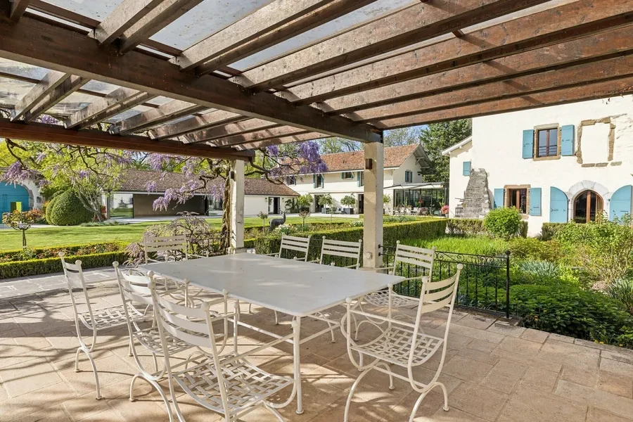 Pergola terrace with garden dining area overlooking château grounds with wisteria