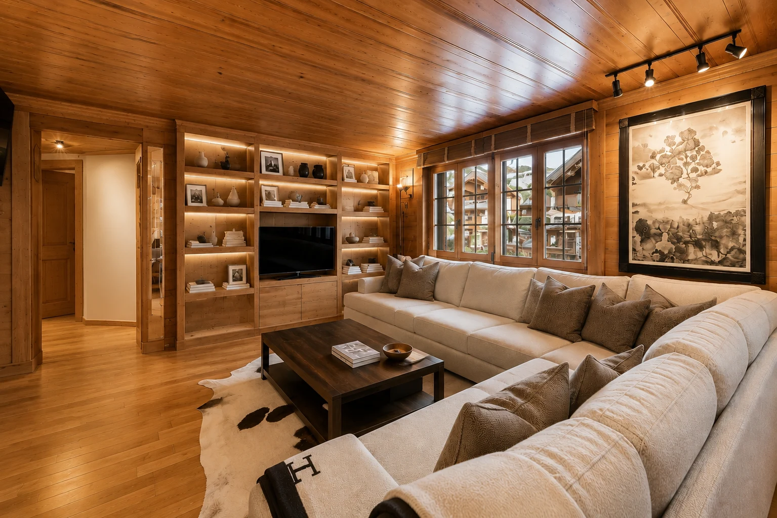 Séjour alpin raffiné avec bibliothèque intégrée et plafond en bois dans un appartement à Gstaad